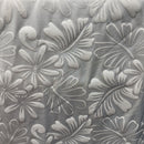 Close-up view of 3D botanical leaf print polyester fabric featuring raised white textured tropical leaves and hibiscus flowers.