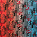 A flat-lay view of a Fijian Tapa Barkcloth Fabric (Style 2) featuring a traditional geometric pattern. The design consists of repeating rectangular tiles in a vibrant gradient of red, white, and light blue, filled with intricate black tribal motifs including sunbursts, triangles, and linear hatches.