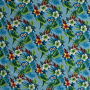 Tropical floral pattern featuring clusters of white, orange, and red hibiscus flowers with green leaves on a vibrant light blue background.